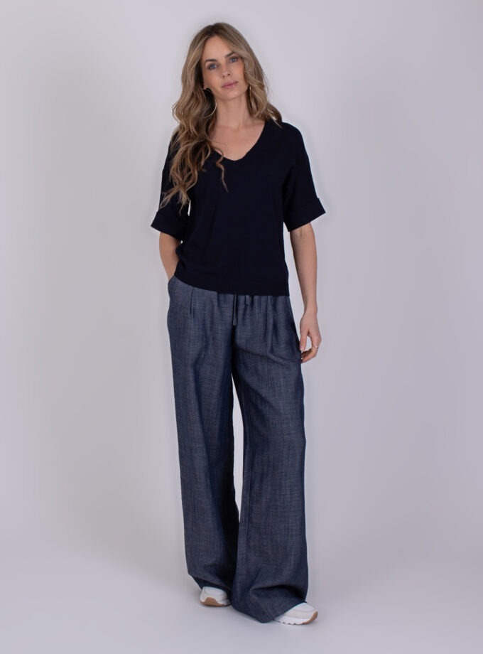 Vrouw draagt een donkerblauwe Pylos Navy 2 outfit met een losvallende top en wijde broek.