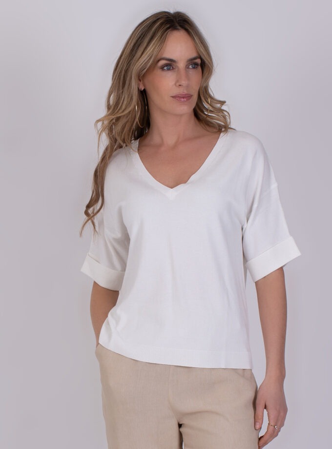 Vrouw draagt de Pylos off white top met V-hals en opgerolde korte mouwen.
