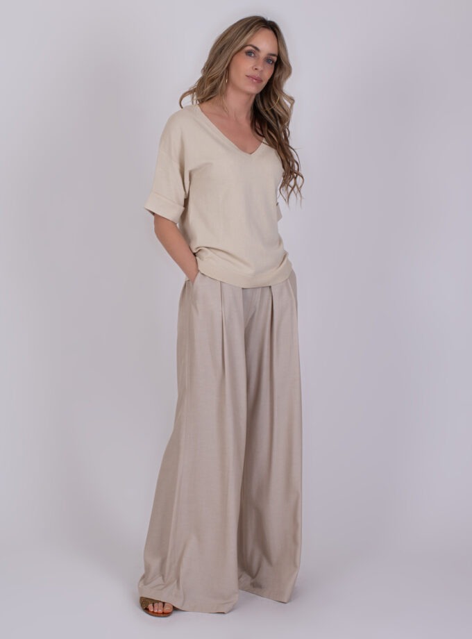 Vrouw in beige outfit met wijde Pylos Pale 3 broek en V-hals top.