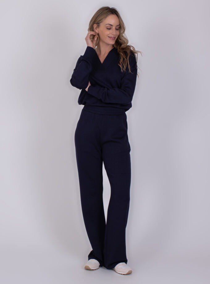 Vrouw draagt een donkerblauwe Rimini Navy 3 lounge-set met lange mouwen en wijde broek.