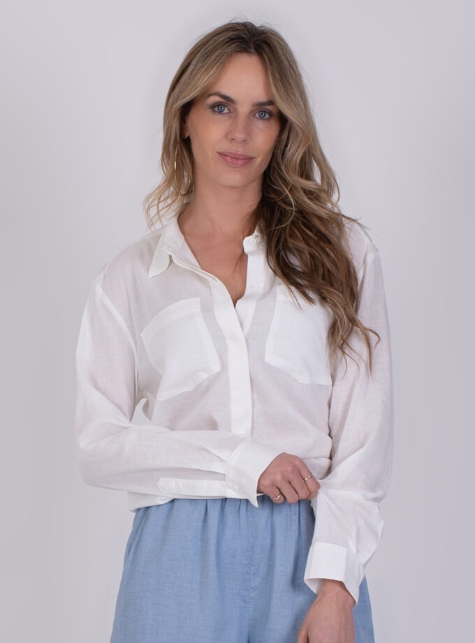 Vrouw draagt een lichte Seoel off white blouse met lange mouwen en lichtblauwe broek.