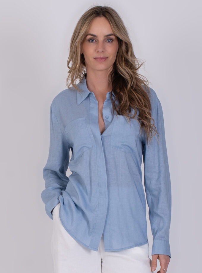 Vrouw draagt een lichtblauwe Seoel-blouse met lange mouwen en een casual pasvorm.