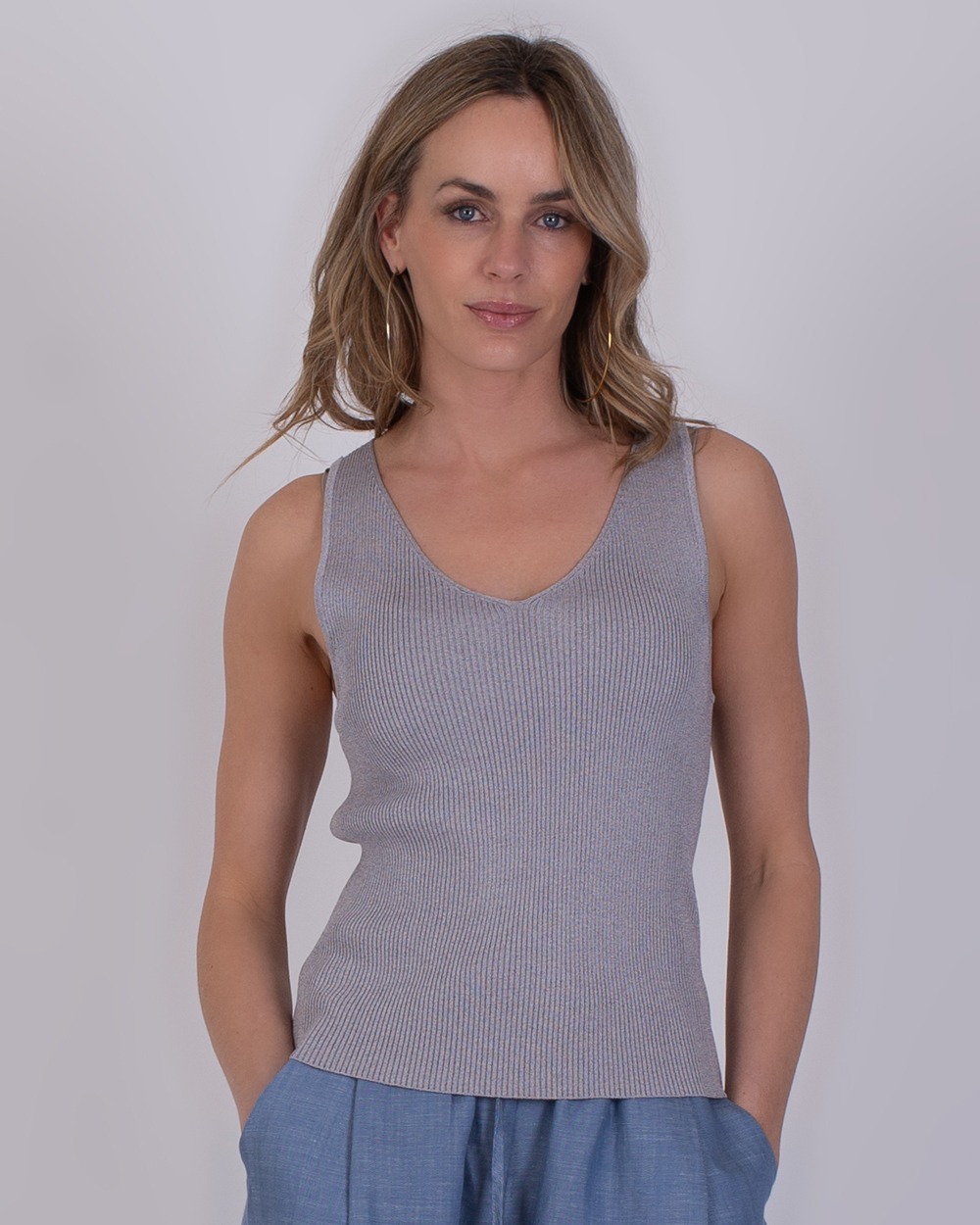 Vrouw draagt een grijs, mouwloos ribgebreid topje genaamd Serres grey 4 met V-hals.