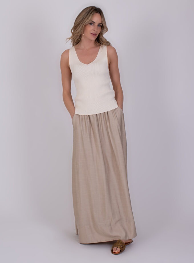 Vrouw draagt de Serres Pale 4 outfit met een gebroken witte top en een lange, beige rok.
