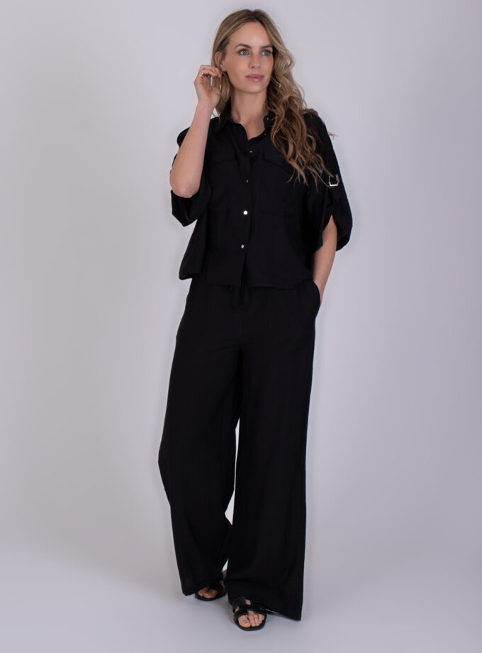 Vrouw draagt een zwarte Soppron-set met wijde broek en halflange blouse.