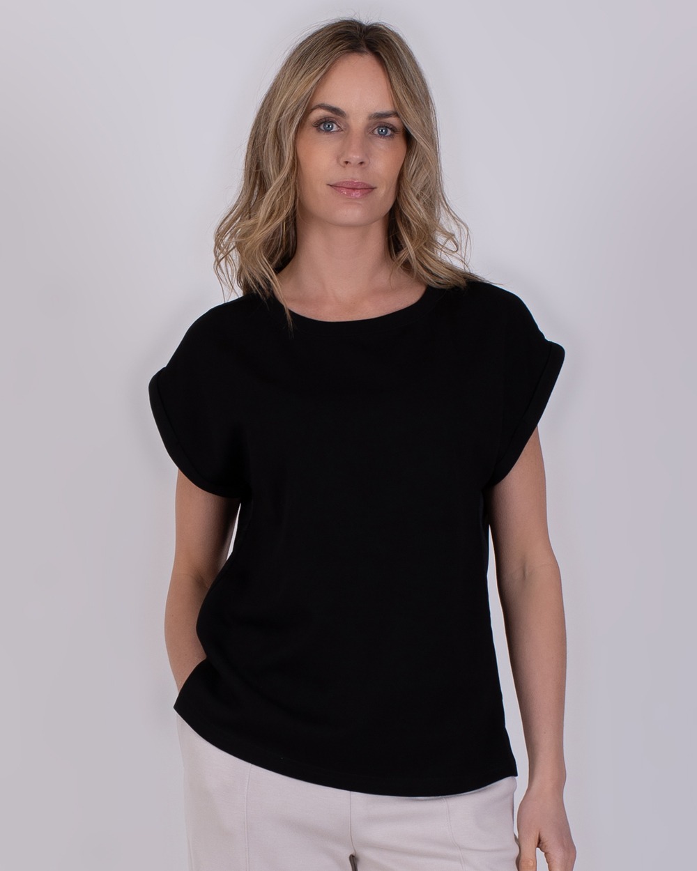 Vrouw draagt een zwarte Troje-top met opgerolde mouwen en een ronde hals.