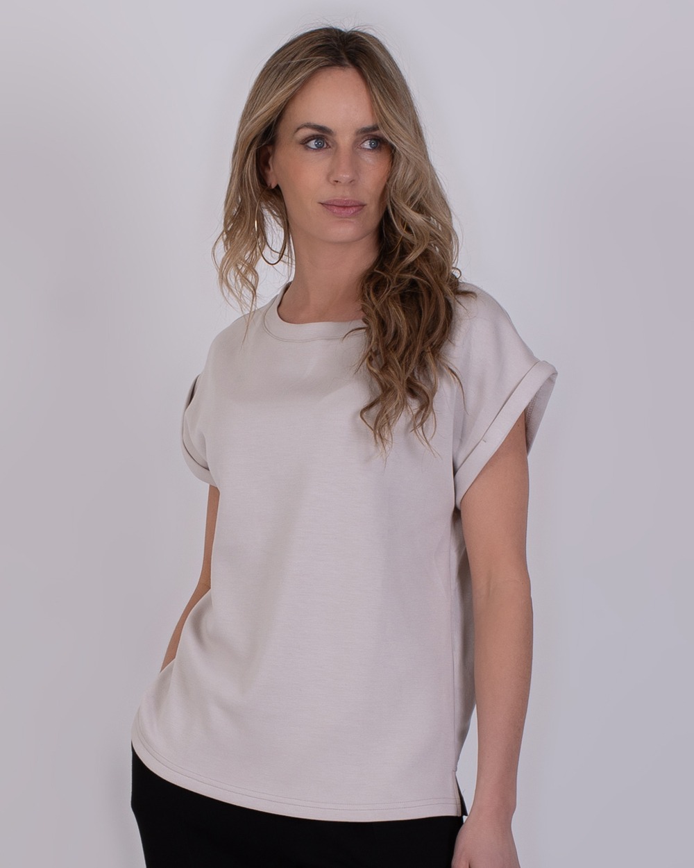 Vrouw draagt een lichtbeige Troje Kit 3 T-shirt met omgeslagen mouwen.