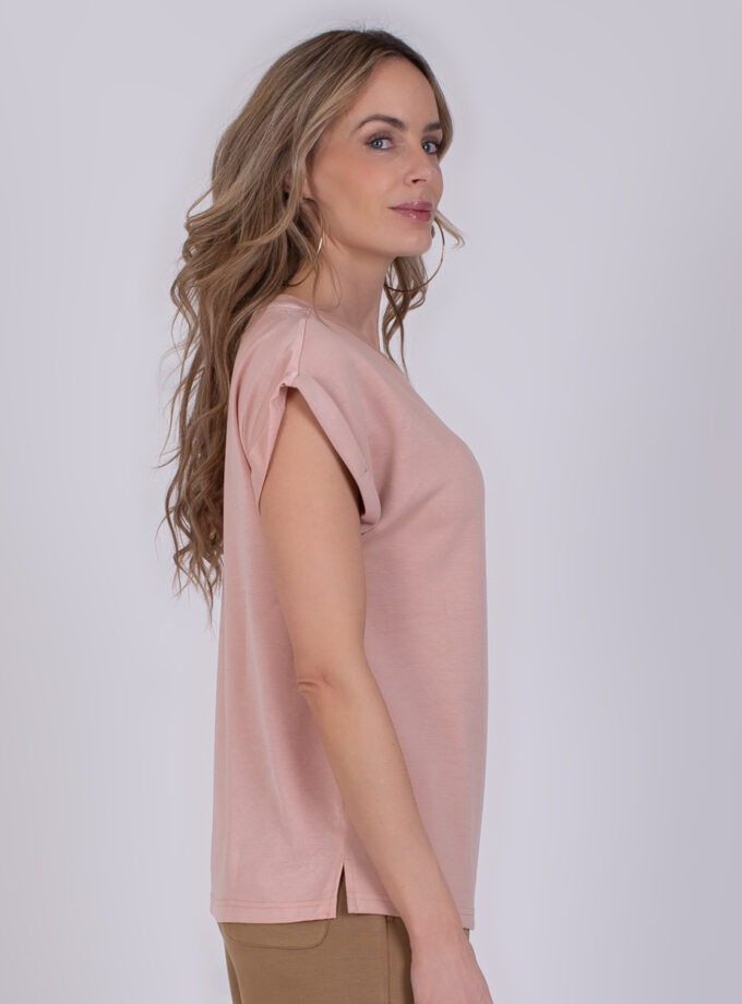 Vrouw in zijaanzicht draagt een oudroze Troje T-shirt met opgerolde mouwen.
