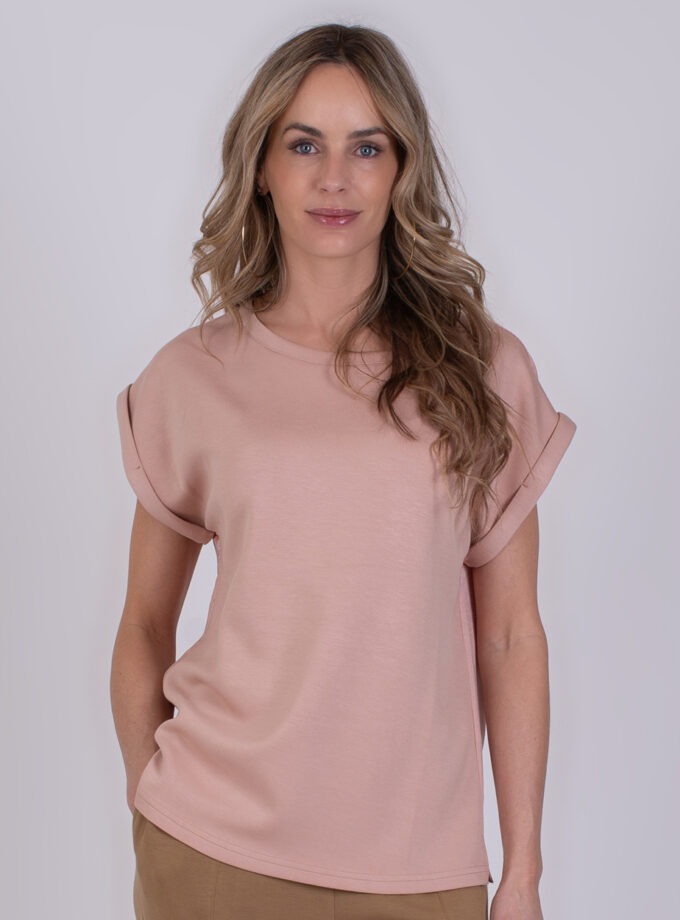 Vrouw draagt een roze Troje T-shirt met opgerolde mouwen.