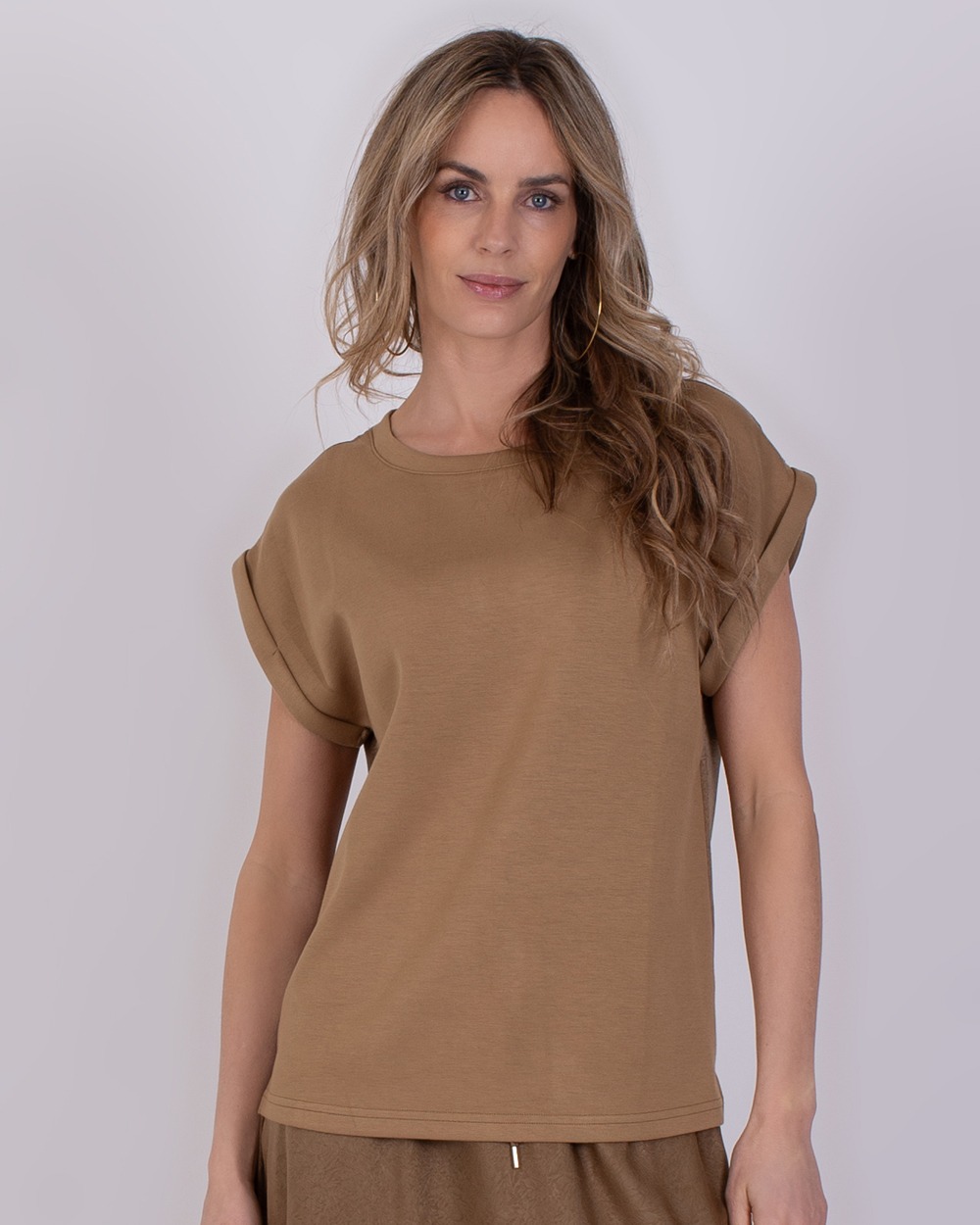 Troje taupe 2 Vrouw draagt een taupekleurige top met opgerolde mouwen uit de collectie Troje taupe.