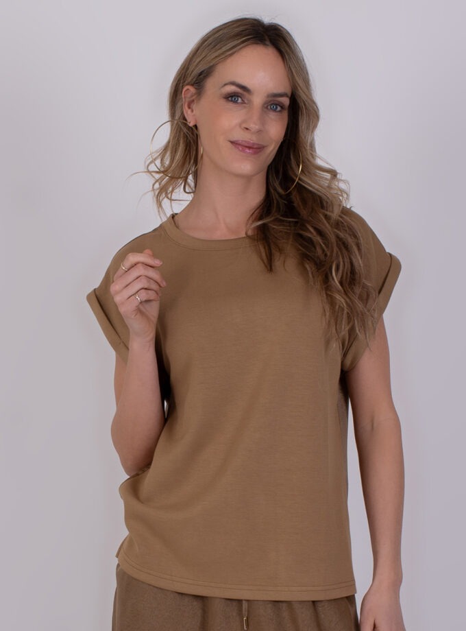 Vrouw draagt een taupekleurige Troje-top met omgeslagen mouwen.