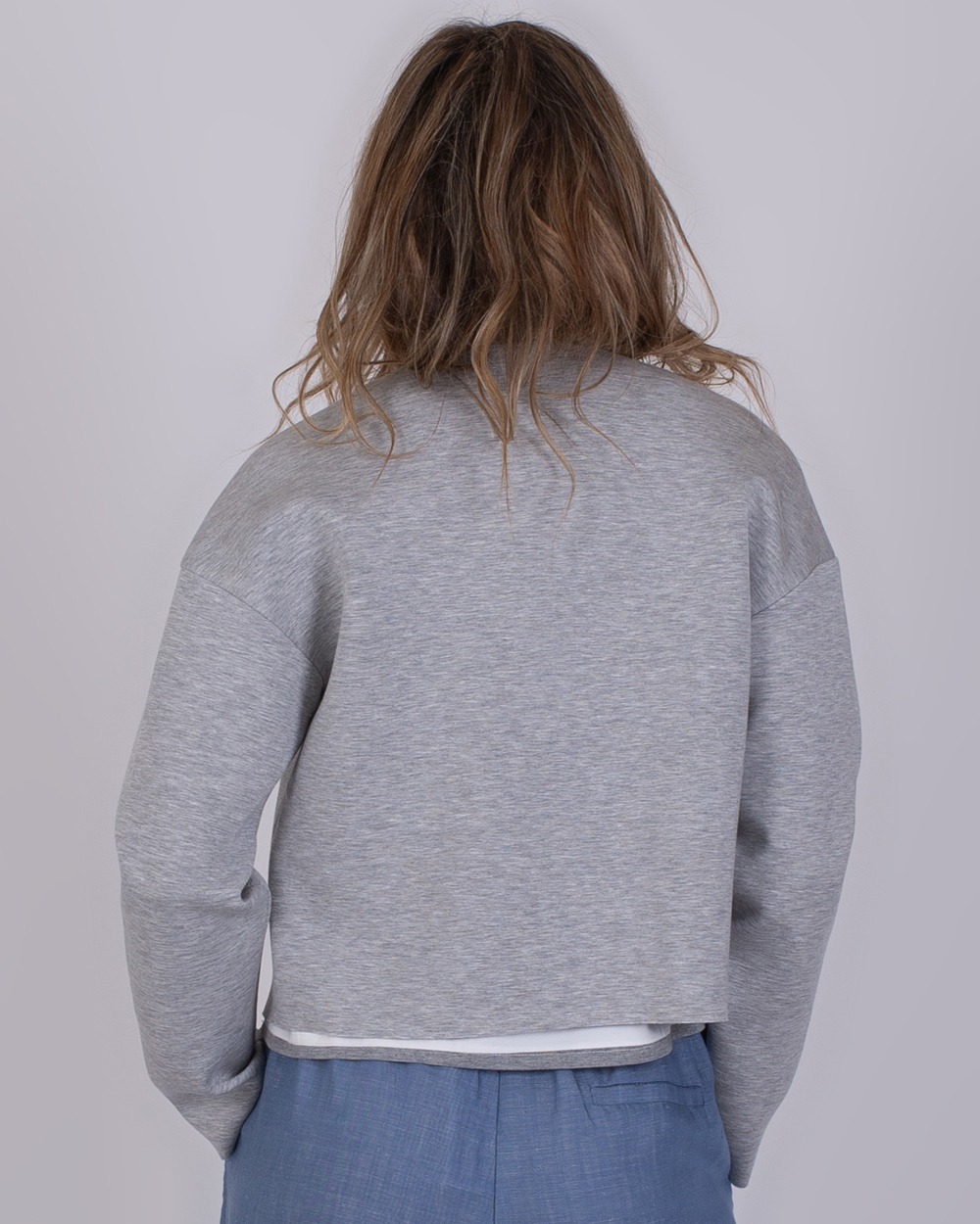 Tule grey 4 Achteraanzicht van een persoon die een grijze Tule Grey trui en een blauwe broek draagt.