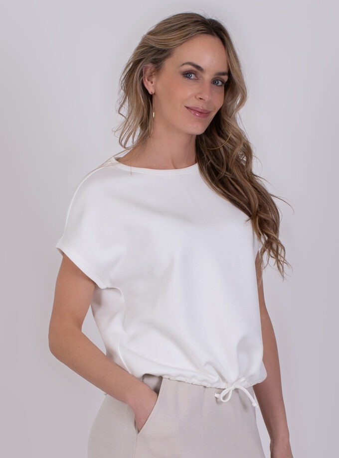 Vrouw draagt een off-white Umea top met korte mouwen en trekkoord in de taille.