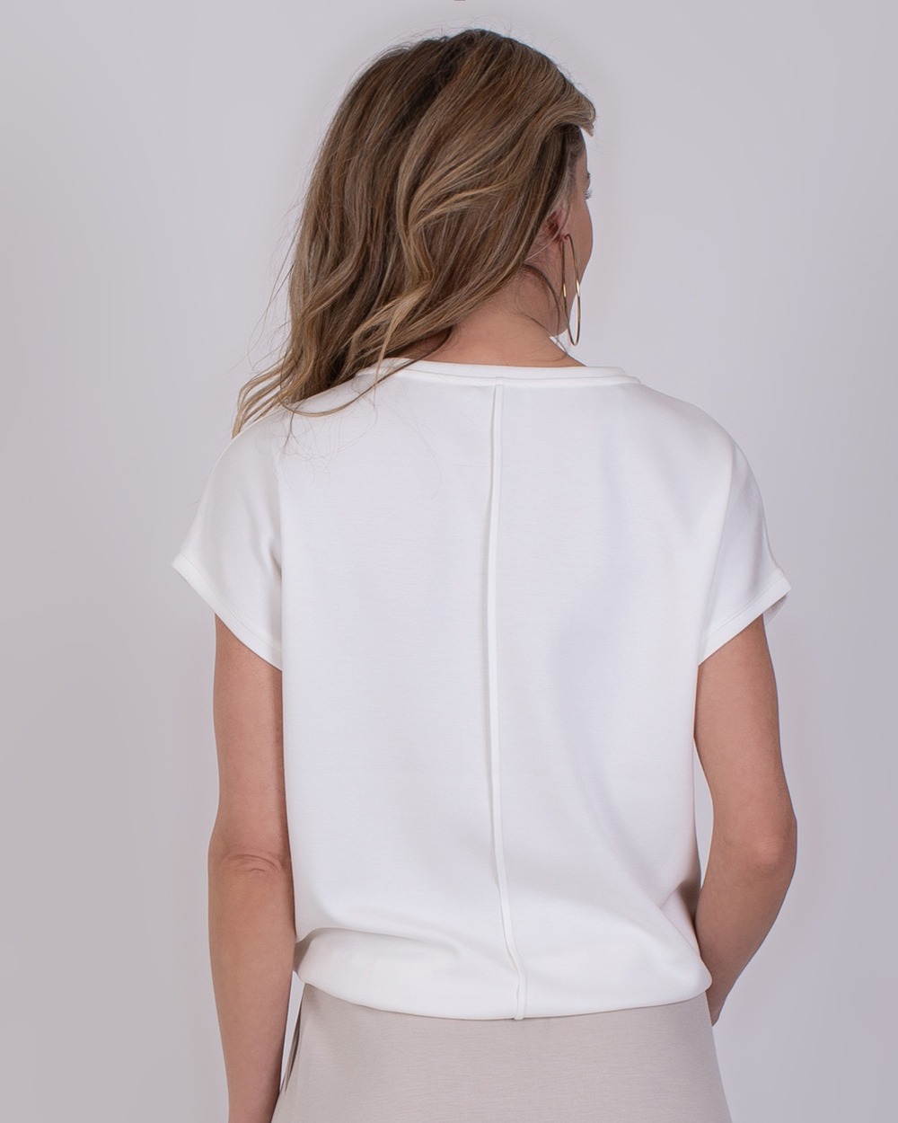 Umea off white 4 Achteraanzicht van een vrouw die de offwhite Umea-top met korte mouwen draagt.