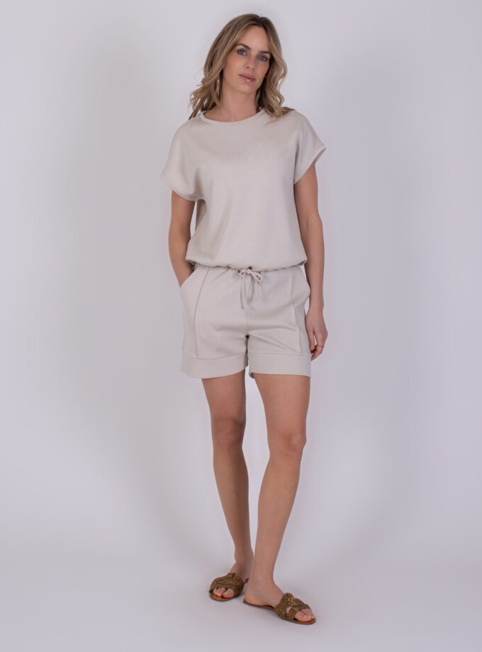 Vrouw draagt een lichtbeige Umea Pale 1 set met T-shirt en korte broek.