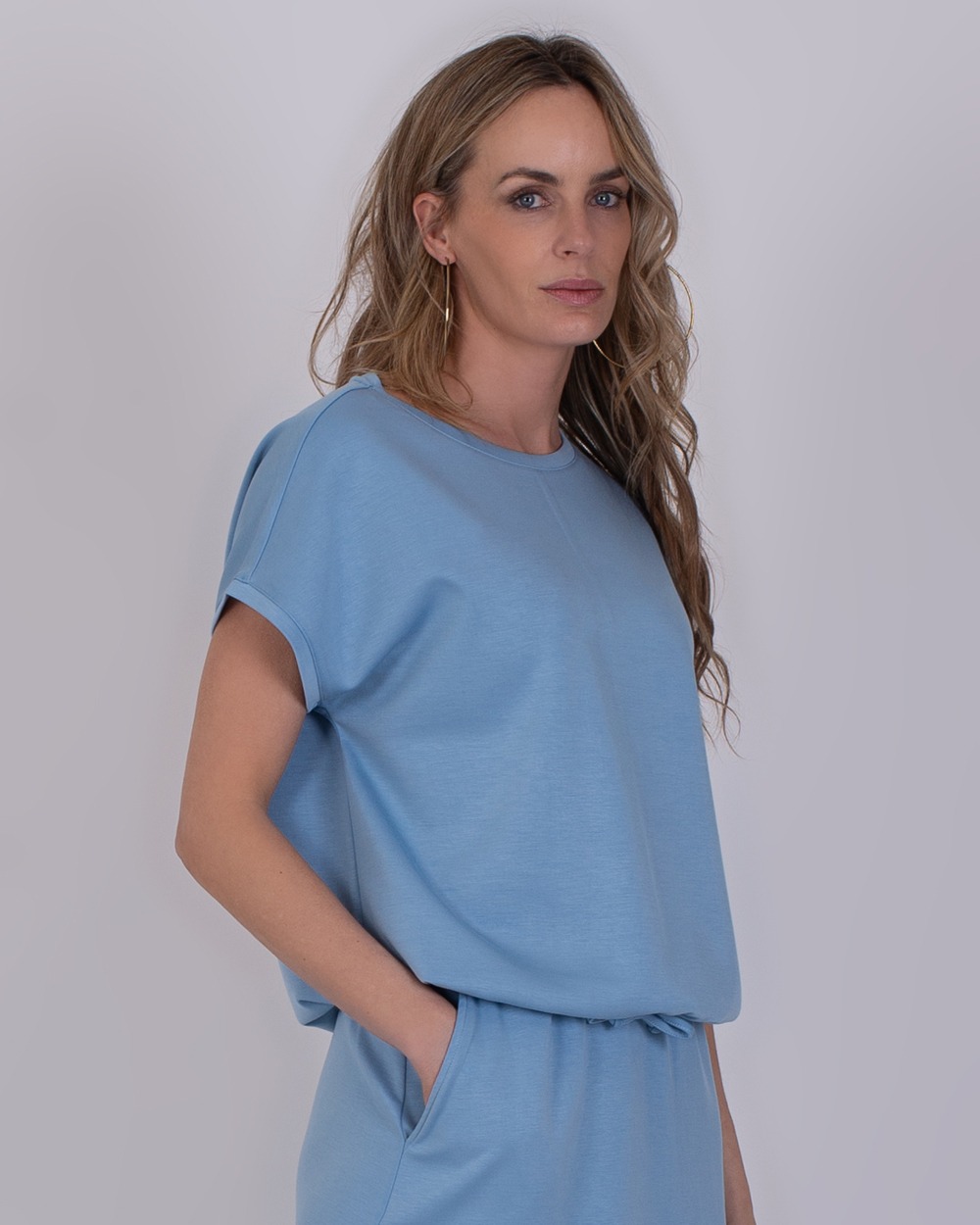 Umea soft blue 3 Vrouw draagt een comfortabele, lichtblauwe Umea soft blue set met korte mouwen en een relaxte pasvorm.
