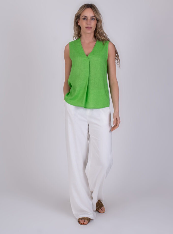 Vrouw draagt een mouwloze Valdris Sea Green top met V-hals en wijde witte broek.