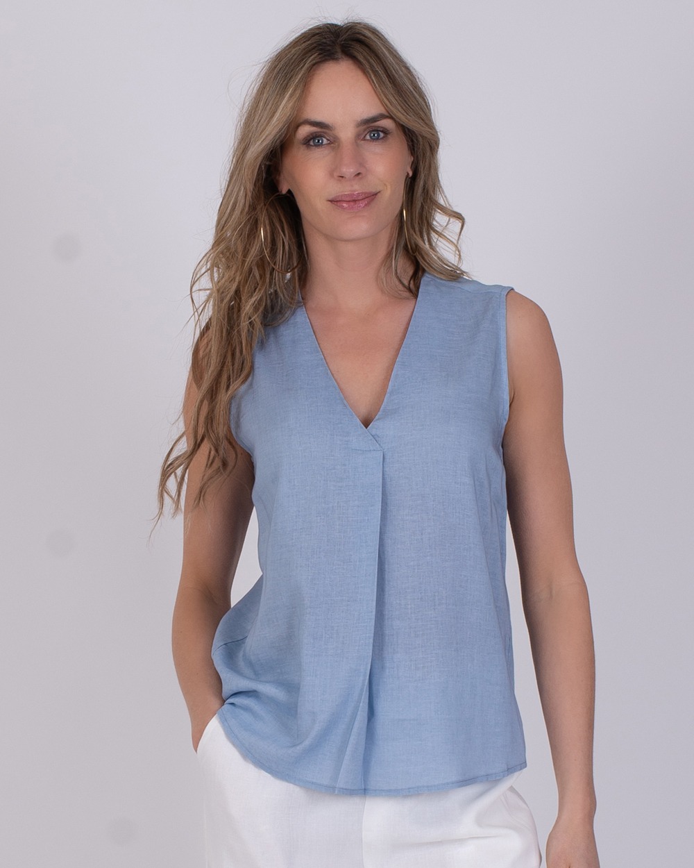 Vrouw draagt een mouwloze, lichtblauwe Valdris top met V-hals.