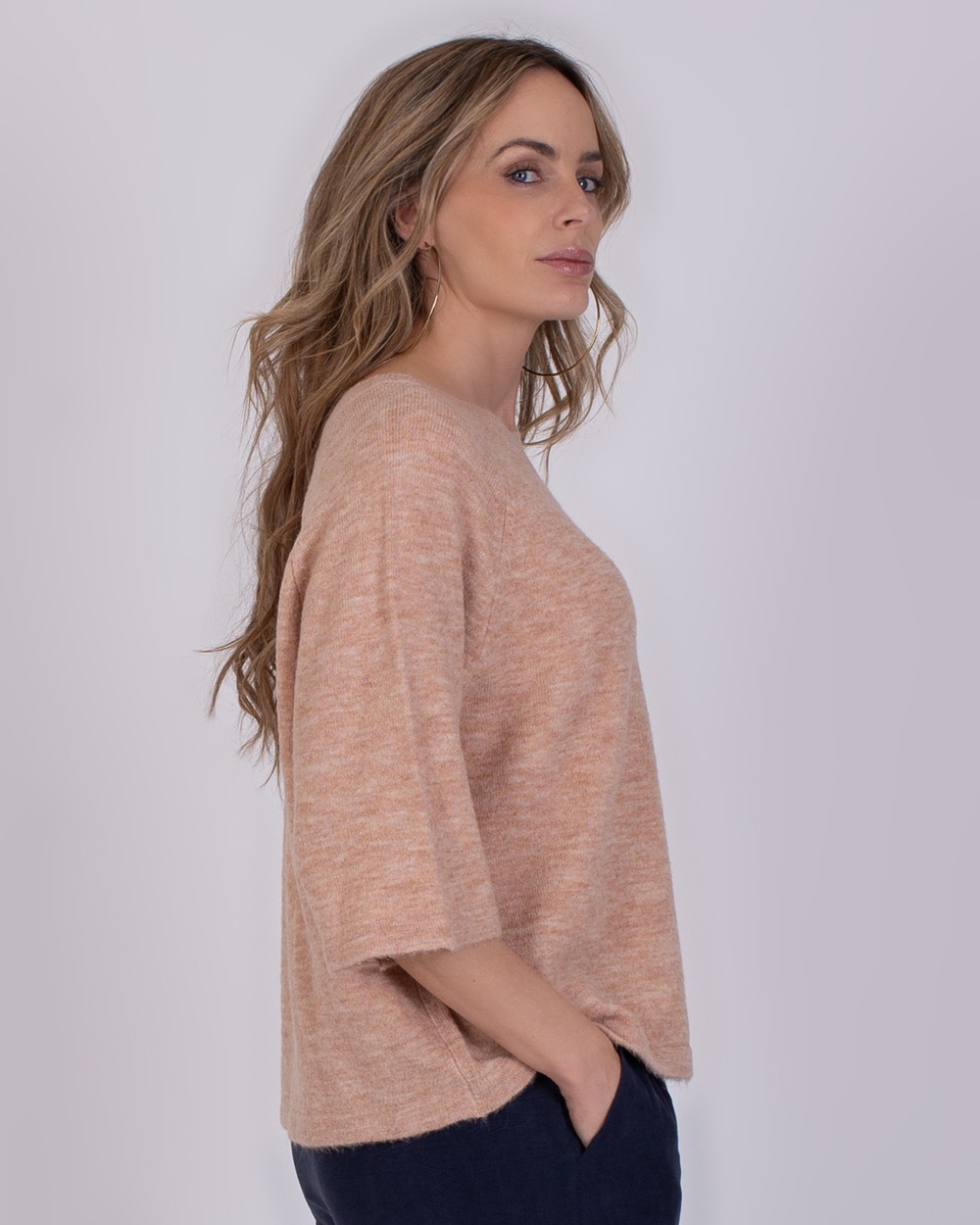 Vrouw in zijaanzicht draagt een losvallende trui in de kleur Volos old pink.
