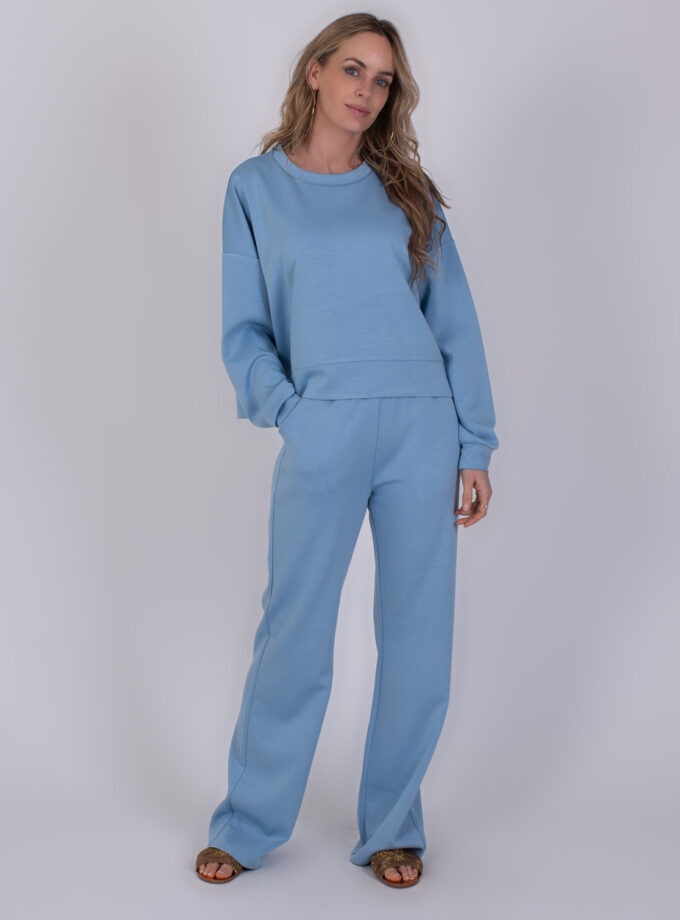 Vrouw draagt een comfortabele, lichtblauwe York soft blue set bestaande uit een sweatshirt en wijde broek.