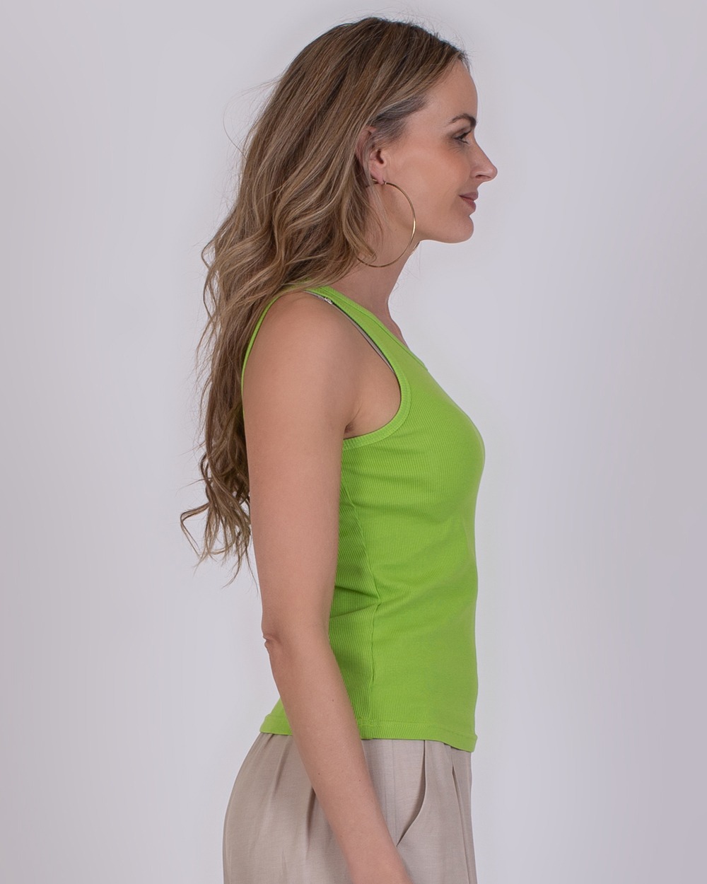 Ypres lime 3 Vrouw in profiel draagt een limegroene Ypres-top met beige broek.