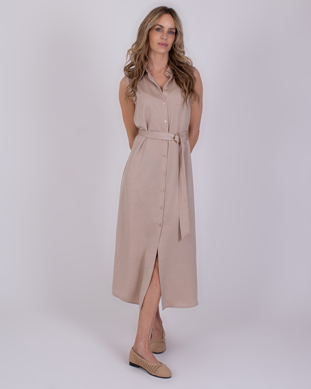 Zaria pale 1 Vrouw draagt een mouwloze, lichtbeige Zaria Pale 1 doorknoopjurk met ceintuur.