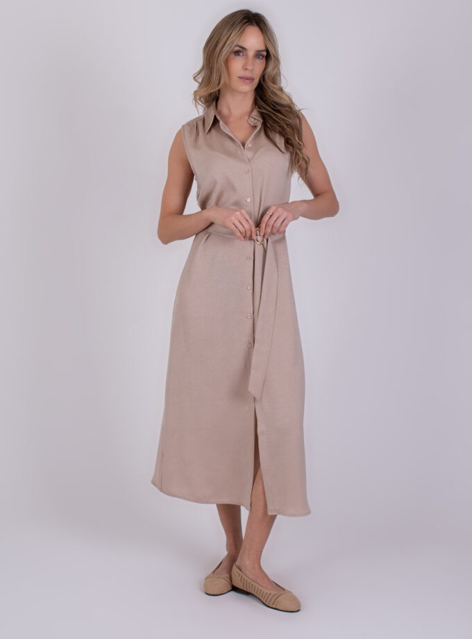 Vrouw poseert in een mouwloze, lichtbeige Zaria Pale 3 doorknoopjurk met ceintuur.