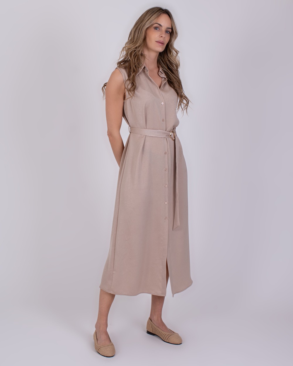 Zaria pale 4 Vrouw draagt een mouwloze, licht beige Zaria Pale 4 doorknoopjurk met ceintuur.
