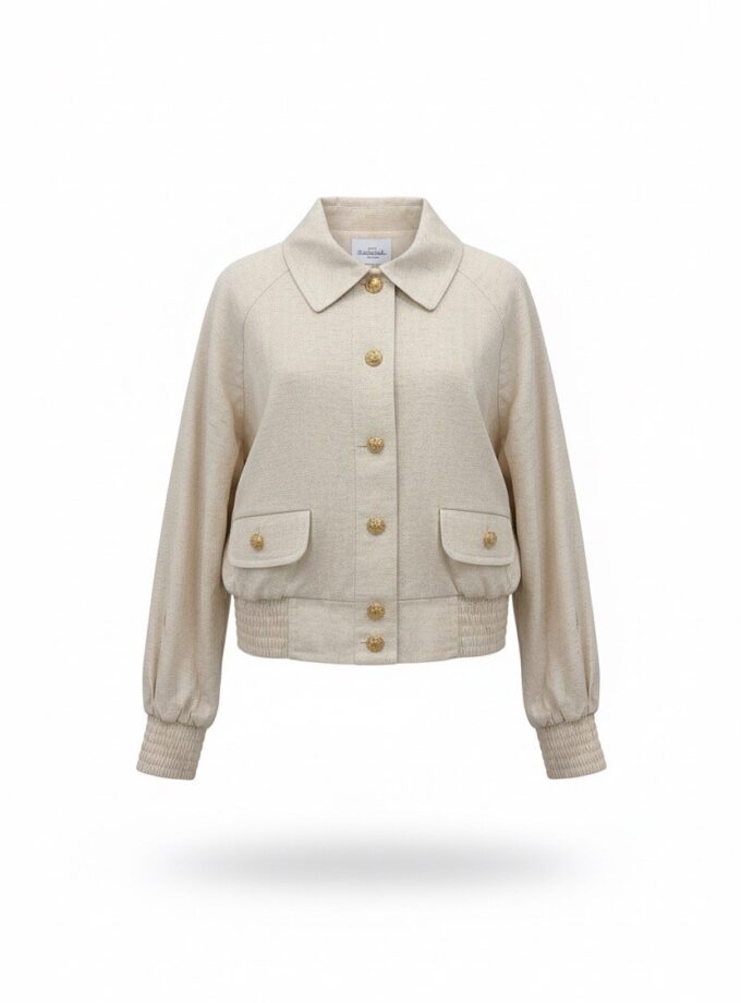 Beige damesjas met goudkleurige knopen en twee voorzakken, geplaatst voor een witte achtergrond.