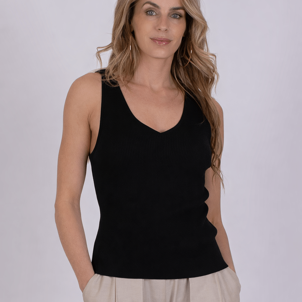 Vrouw met los haar draagt een zwarte mouwloze top tegen een neutrale achtergrond.