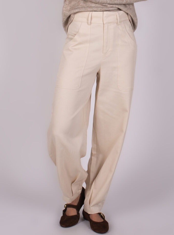 Beige, wijde broek genaamd "Balam pant-118" gedragen met bruine schoenen en een gedrapeerde trui, vanuit een hoek recht van voren.