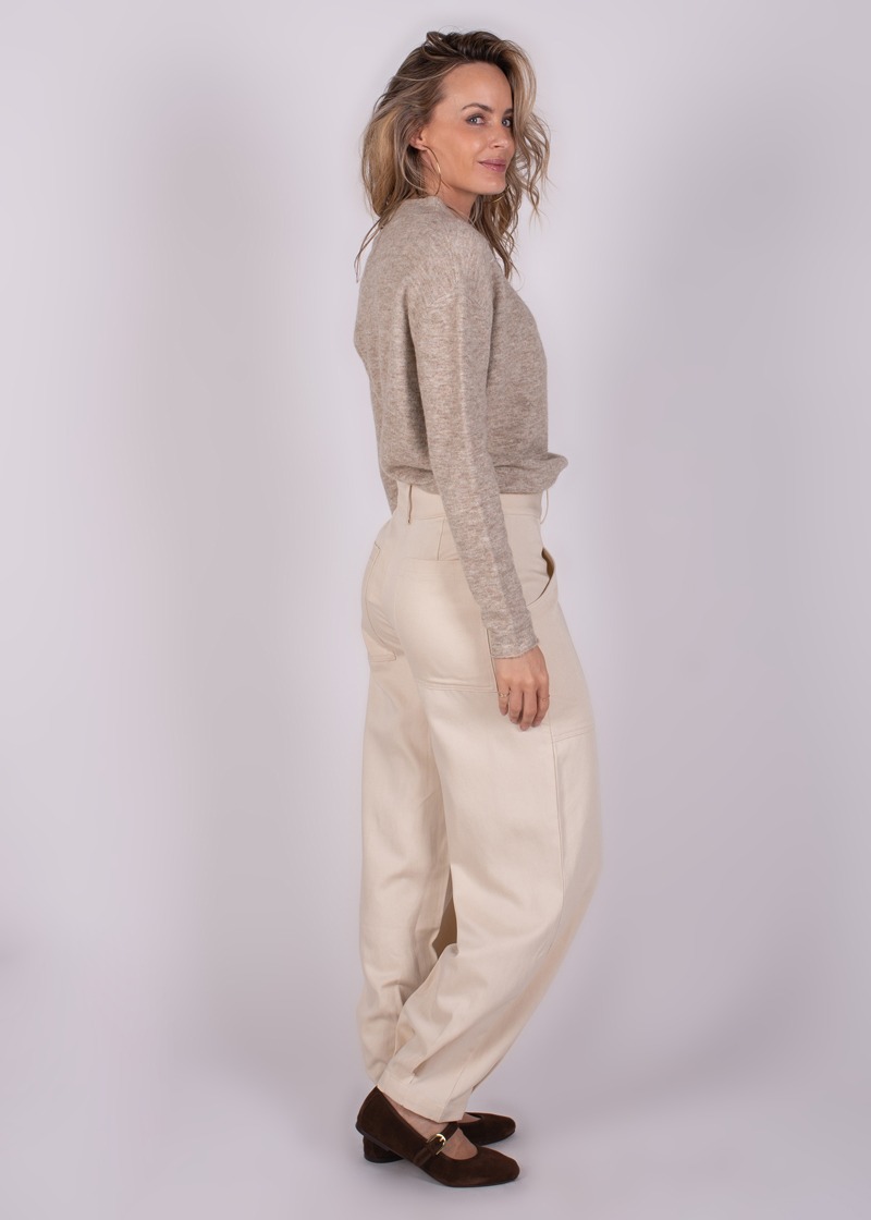 Een vrouw in een beige trui en crèmekleurige Balam pant-120 broeken, gefotografeerd van een zijaanzicht.