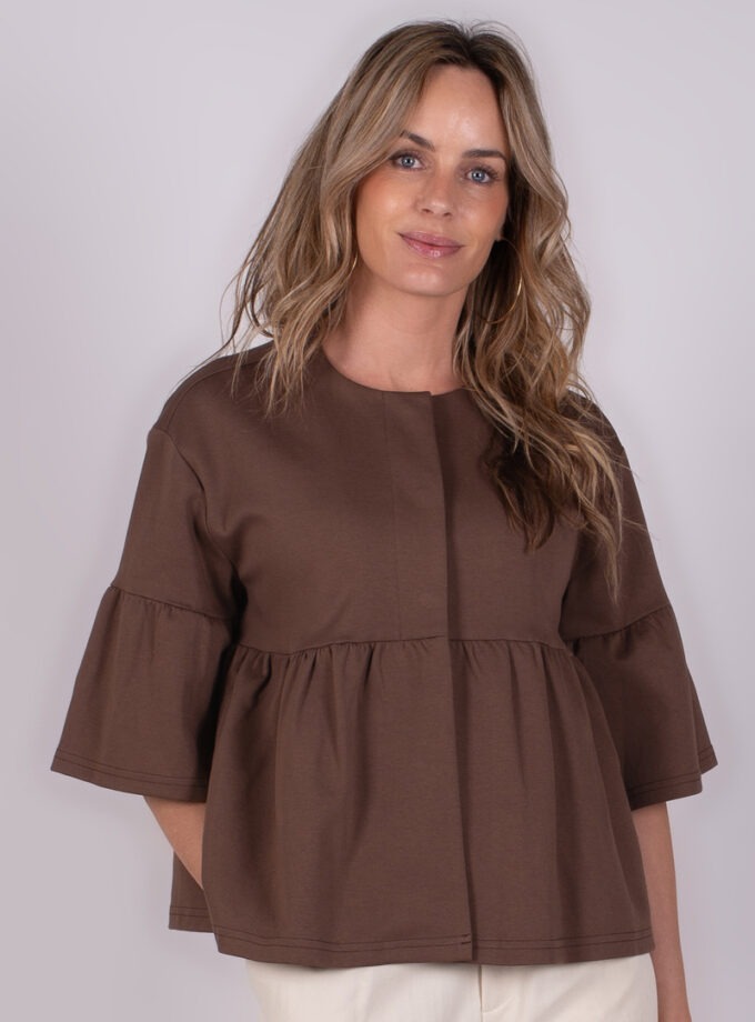 Model draagt een bruin Bilbao top met driekwart mouwen en een geplooid design, tegen een neutrale achtergrond.
