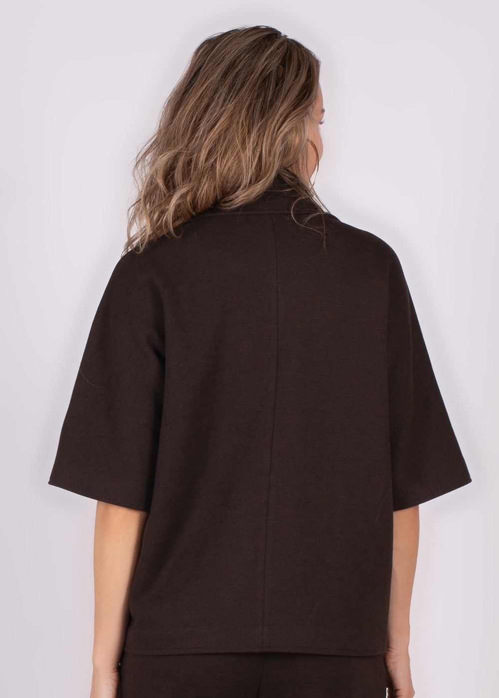 Achteraanzicht van een vrouw die een bruine Helsinki-blazer met korte mouwen draagt.