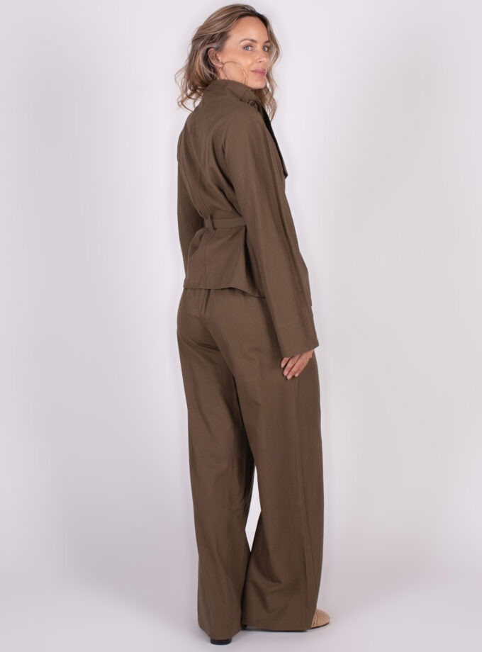 Model in een bruin Hobart blazerjasje en bijpassende broek, gezien van schuin achteren tegen een witte achtergrond.