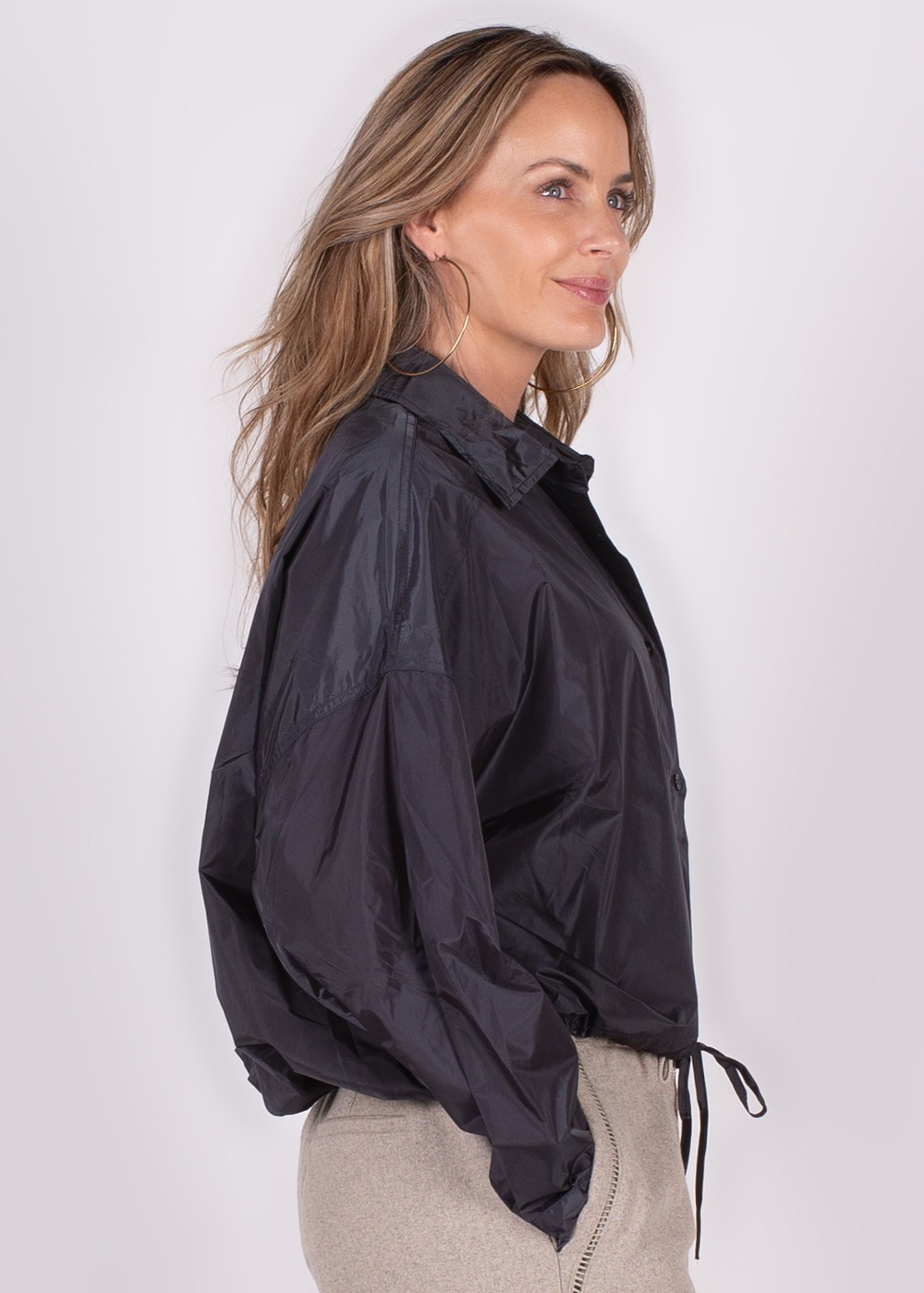 Model draagt een zwarte Lubia blouse met kraag en lange mouwen, vanuit een zijaanzicht gefotografeerd.
