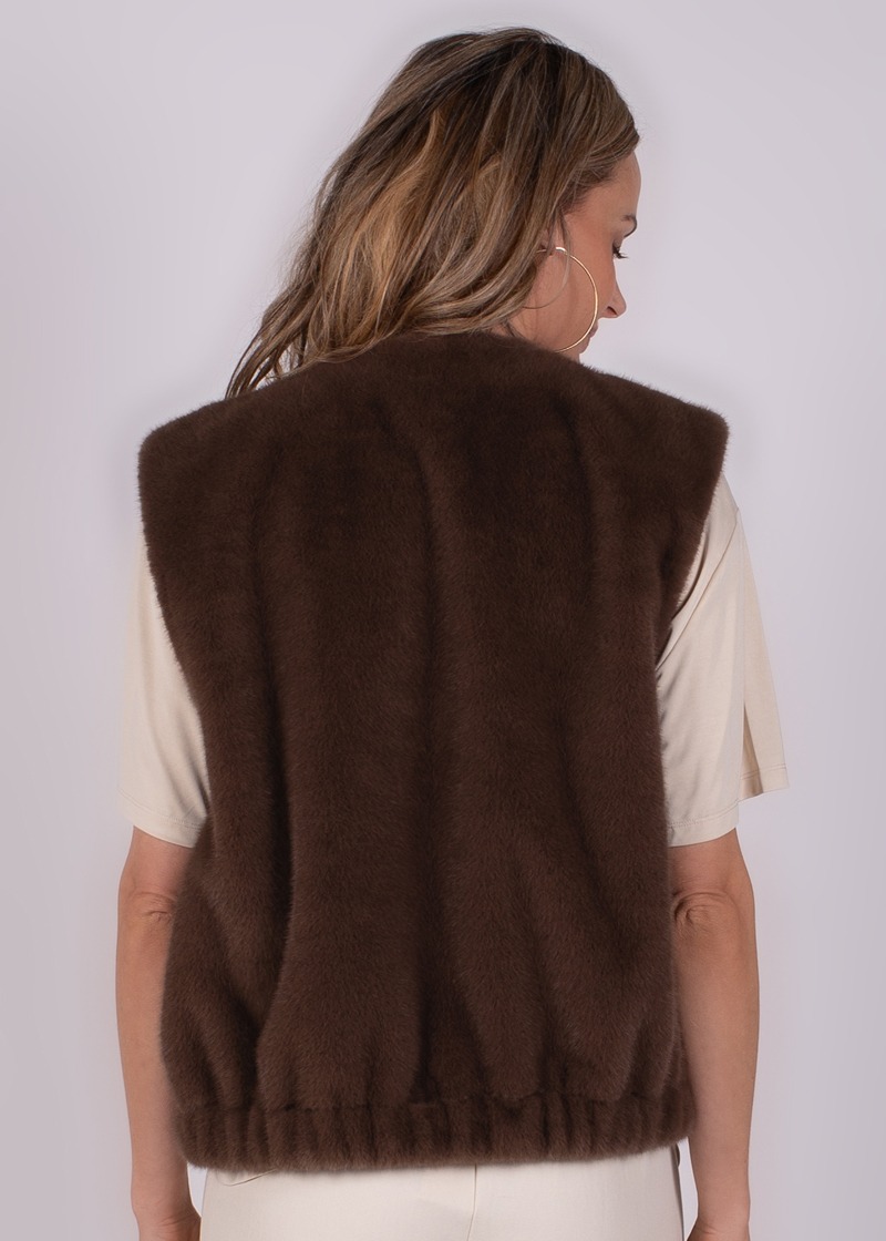 Achteraanzicht van een vrouw die een crèmekleurige Milan short sleeve tee draagt onder een donkerbruine, harige mouwloze vest.