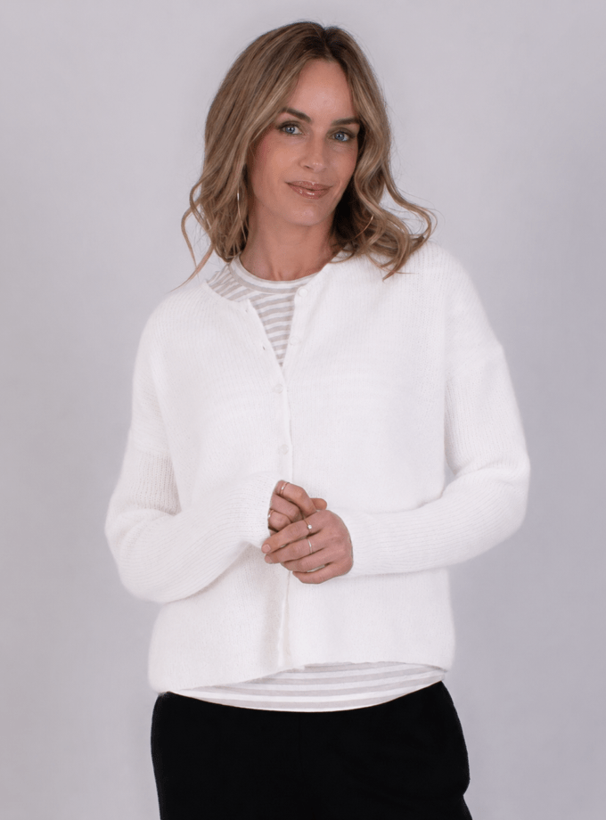 Vrouw met los haar draagt een off-white vest genaamd "Narvik" over een gestreept shirt, tegen een neutrale achtergrond.