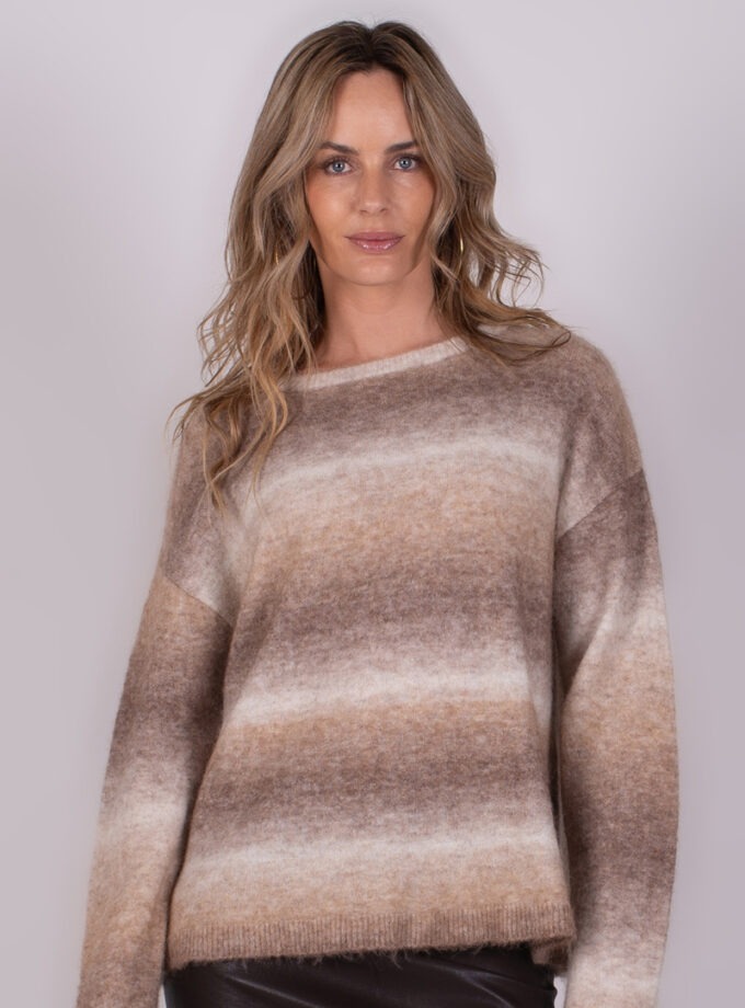 Vrouw in een bruin-beige gestreepte trui tegen een neutrale achtergrond, frontaal gefotografeerd.