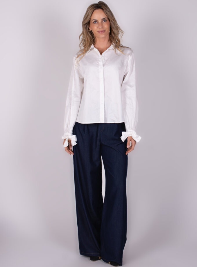 Model draagt een witte Perth blouse met lange mouwen en een donkere broek, frontaal gefotografeerd.