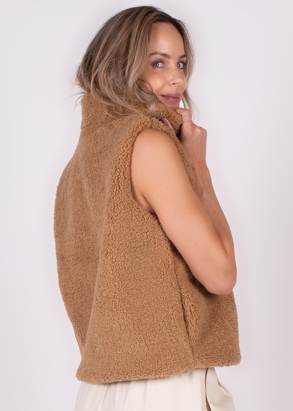 Een model poseert in zijaanzicht met een bruin teddy gilet genaamd "Regina gilet-139".