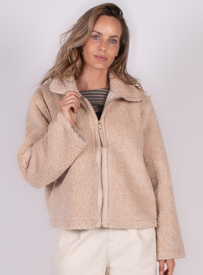 Een vrouw poseert in een crèmekleurige Regina gilet met een ritssluiting, gefotografeerd van voren tegen een neutrale achtergrond.