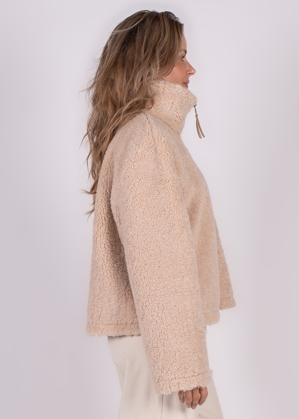 Model in zijaanzicht draagt een beige fleece gilet genaamd "Regina gilet pale-183" met hoge kraag en ritssluiting.