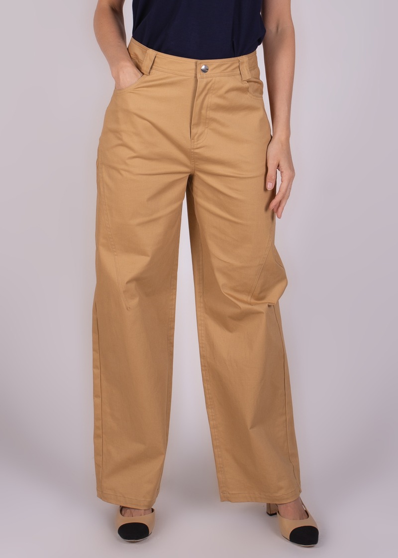 Model draagt beige wijde Vienna broek, gezien van voren tot aan de enkels, gecombineerd met een donkerblauw shirt.
