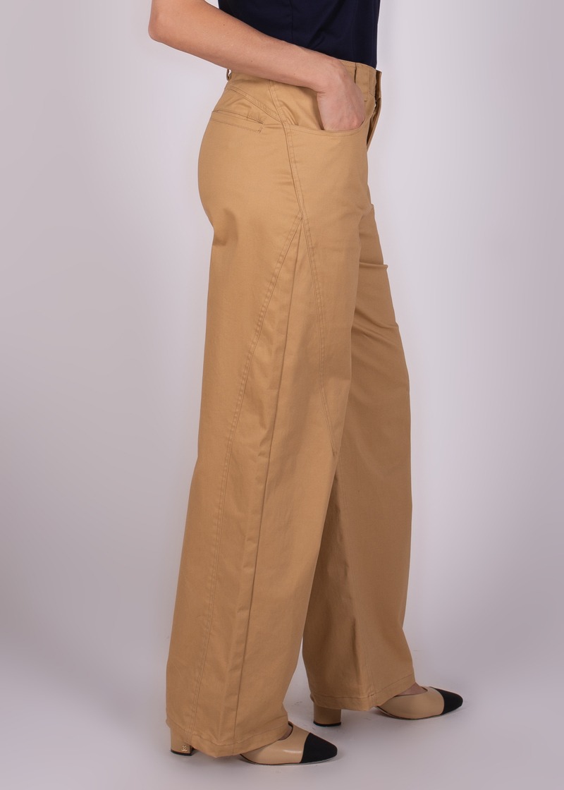 Een model draagt beige wide-leg Vienna pants met één hand in de zak, gezien vanuit een zijaanzicht.